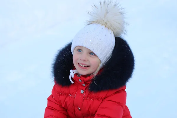 Portret van een lachende meisje in een hoed met een grote bont pompom winter — Stockfoto