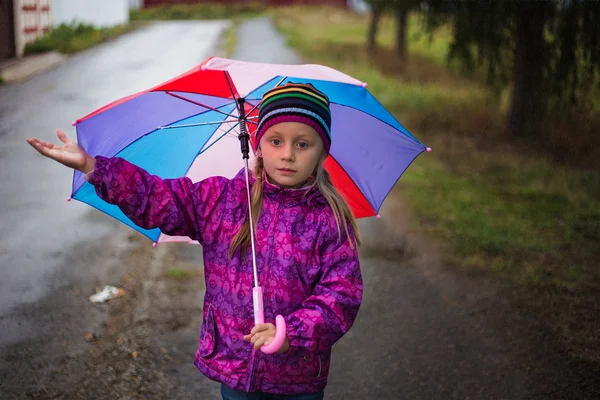 Chica caminando bajo la lluvia bajo un paraguas — Foto de Stock