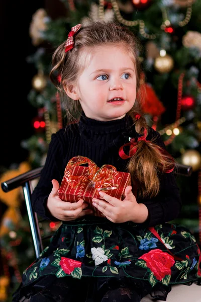 Милая маленькая девочка крупным планом с новогодним подарком в руках — стоковое фото