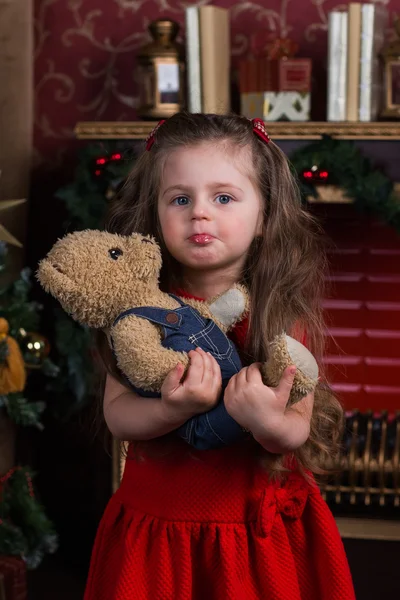Красивая девушка с длинными волосами, стоящая рядом с елкой с любимым игрушечным медведем — стоковое фото