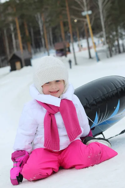 冬時間で女の子が雪の上に乗ってスライドします。 — ストック写真