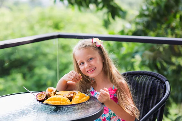 Sweet girl eating fruits on the terrace for breakfast on holiday in Thailand. Здоровые и вкусные блюда подаются на завтрак . — стоковое фото