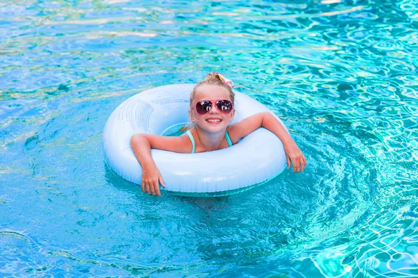 Mała dziewczynka leżąc na kole w basenie na wakacje w słoneczny dzień — Zdjęcie stockowe