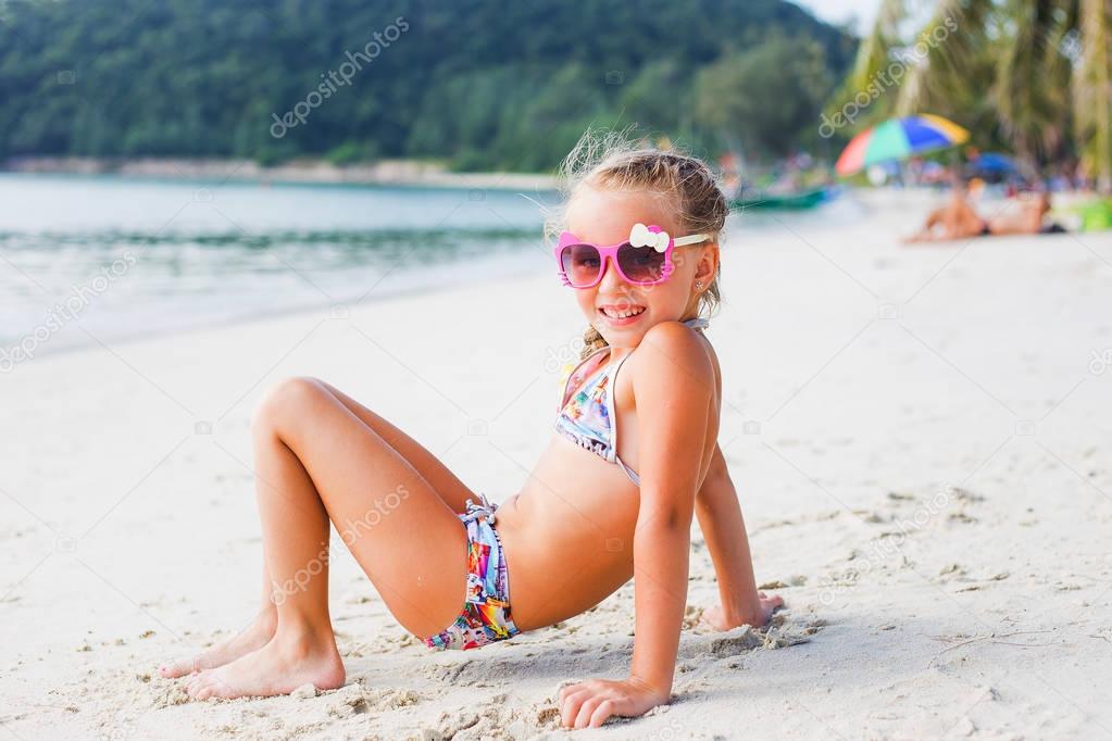 cute little girl in sunglasses and a swimsuit on the beach in paradise by the sea. Travel and Vacation. Freedom Concept. thailand
