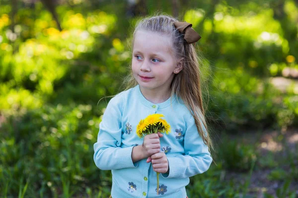 Bonito menina feliz criança andando no parque da primavera e escolhendo dentes-de-leão — Fotografia de Stock