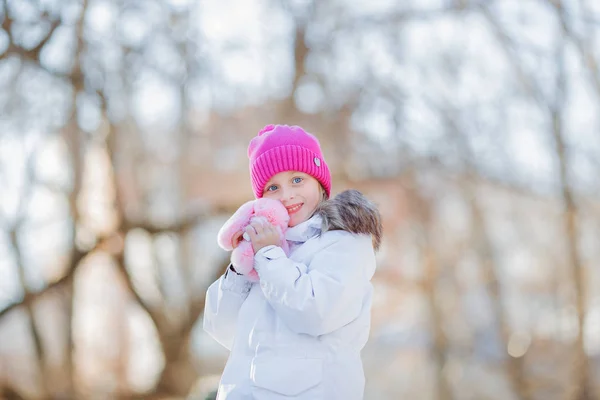 Schöne Mädchen spaziert an einem sonnigen Winternachmittag im Park mit ihrem Lieblingsspielzeug. Konzept der Kinder — Stockfoto