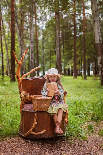 小さな女の子がバスケットに座っていると夏の森でパンします。女の子は空腹. — ストック写真