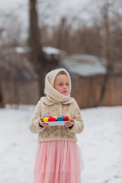 Schönes Mädchen in einem russischen Schal mit bunten Eiern für die Osterfeiertage — Stockfoto