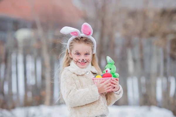 Velikonoční dívka s košíkem vajec a vtipné králíček tvář výraz v lese — Stock fotografie