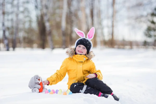 Niedliches Mädchen mit Kaninchen und Körben im Schnee sitzen für wal — Stockfoto