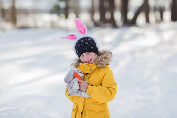 Симпатичная маленькая девочка с кроликом Пасха на белом фоне снега — стоковое фото
