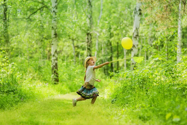 Cute little girl playing net and ball in forest on clearing in summer day — Stock Photo, Image