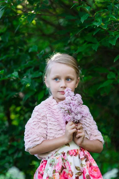 Ritratto di ragazza bionda carina nel parco con alberi di lilla nella giornata estiva — Foto Stock