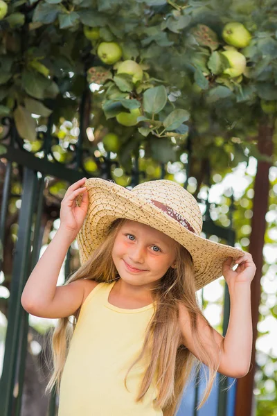 Menina alegre bonita bonito no chapéu com grandes campos no fundo de uma árvore de maçã no dia de verão — Fotografia de Stock