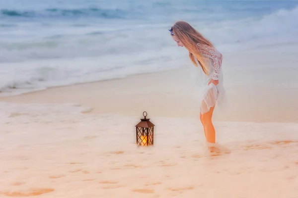 ランタンと海で甘い女の子が立っています。少女とランタンにはねた波. — ストック写真