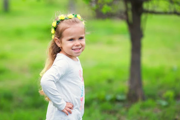 Portrait d'une jolie petite fille dans une couronne de fleurs dans un parc d'été — Photo