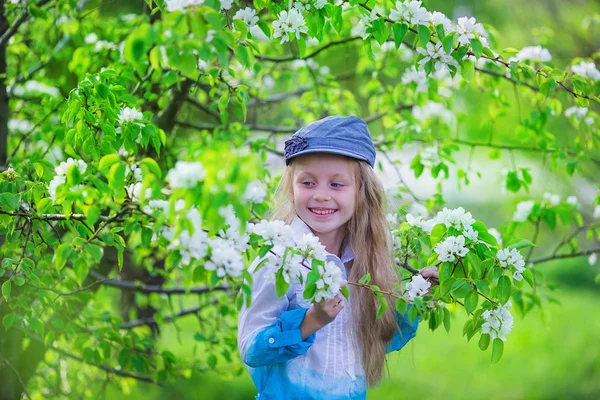 Schattig klein meisje in de buurt van bloeiende appelbomen en cherry — Stockfoto