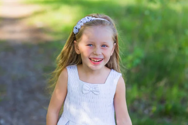 Portrait d'une belle fille souriante aux cheveux longs lors d'une journée d'été en vacances dans le parc — Photo