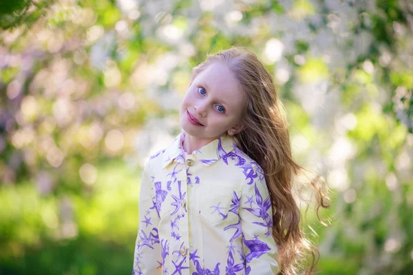 Portrait d'une belle fille mignonne avec de longs cheveux fluides dans un verger de pommiers en fleurs — Photo