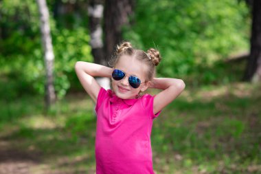 Güneş gözlüklü bir yaz parkta sevimli gülümseyen güzel kız portresi