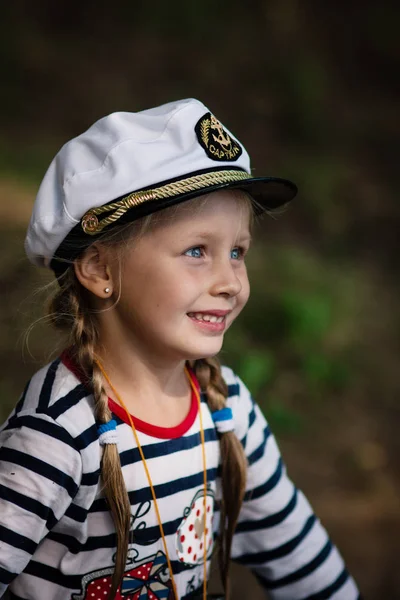 Porträt eines kleinen fröhlichen Mädchens in Matrosenuniform und Seemütze. schließen. — Stockfoto