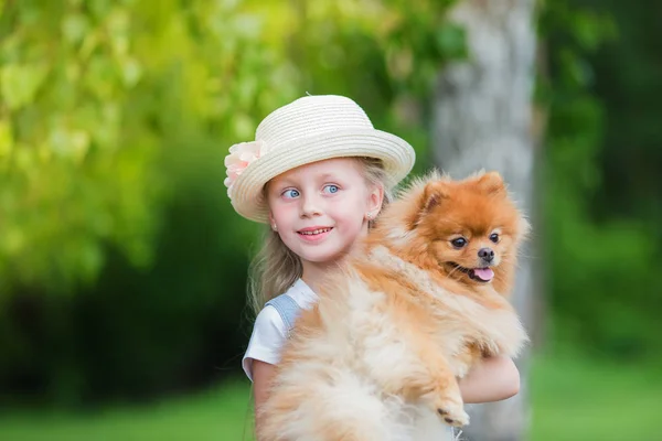 Retrato de uma linda garota com seu cachorro de estimação Spitz em um dia de verão no parque — Fotografia de Stock