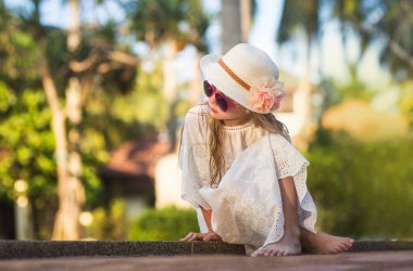 Güzel güzel kız bir şapka ve güneş gözlüğü havuz rahatlatıcı rahatlatır