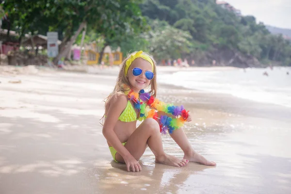 Счастливая девочка улыбается в солнцезащитных очках на пляже у моря — стоковое фото