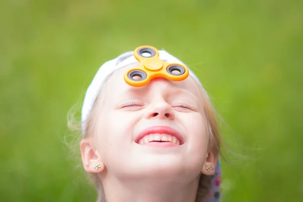 Sonriente chica en la cara jugando con un Tri Fidget Hand Spinner al aire libre — Foto de Stock