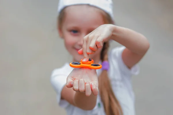 Das Mädchen dreht den Spielzeugspinner mit den Fingern. — Stockfoto