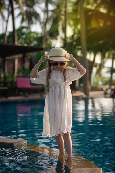 Piękny Ładna dziewczyna w kapeluszu w pobliżu basenu o zachodzie słońca. Paradise — Zdjęcie stockowe