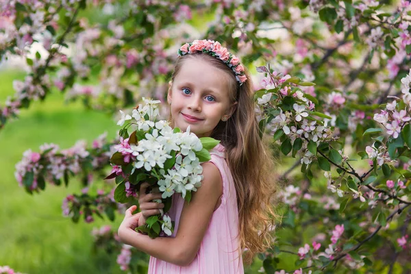 Little happy girl playing under blooming cherry tree with pink flowers. — Stock Photo, Image