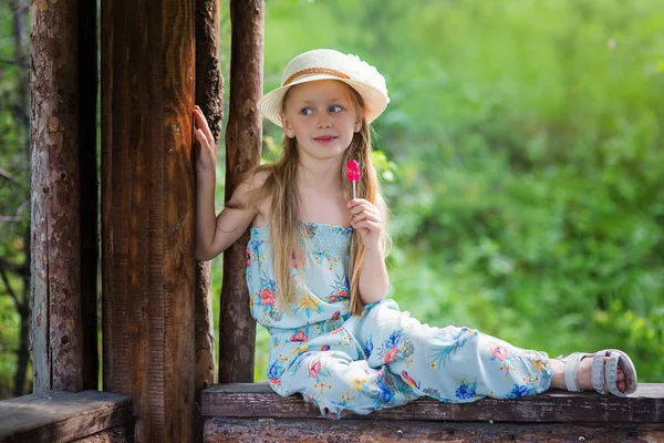 Uma menina com um pirulito senta-se no parque em um dia de verão — Fotografia de Stock