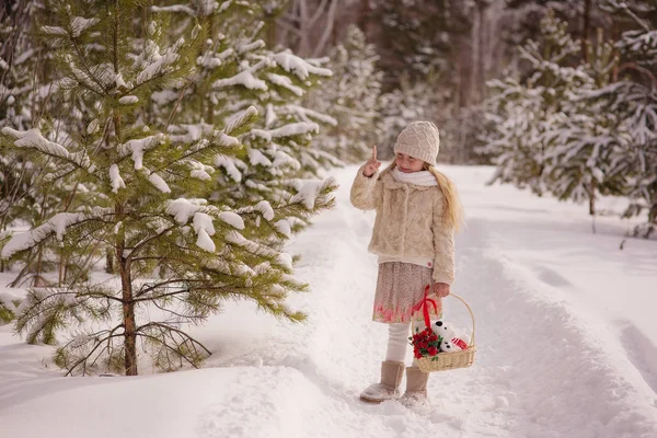 Wesoła dziewczynka gospodarstwa, potrząsając kosz z prezentem w zimowym lesie — Zdjęcie stockowe