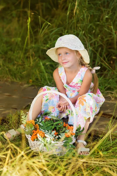 Bir orman yolu rowan bir sepet ile oturan şapkalı sevimli küçük kız — Stok fotoğraf