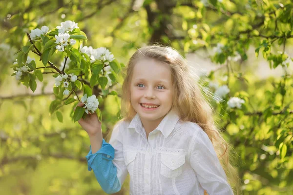 Retrato uma menina bonita um jardim florido na primavera. Criança bonita com cabelo loiro em um jardim florido — Fotografia de Stock