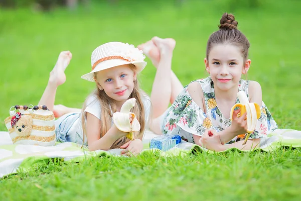 Duas meninas bonitos belo dia de verão relaxante no gramado no piquenique. Piquenique dia de verão no parque . — Fotografia de Stock