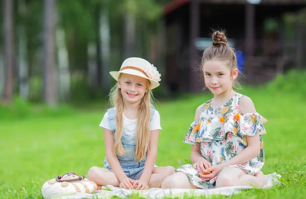 Duas meninas bonitos belo dia de verão relaxante no gramado no piquenique. Piquenique dia de verão no parque . — Fotografia de Stock