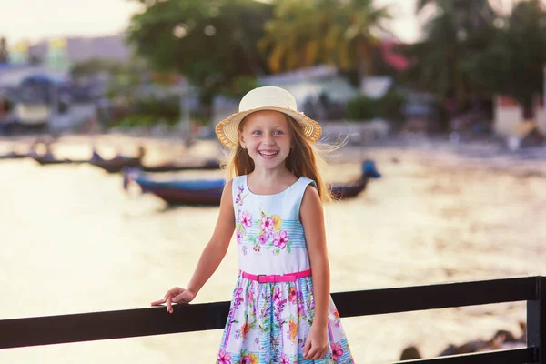 Sweet girl in a hat on vacation in the evening at sunset background Stock Picture