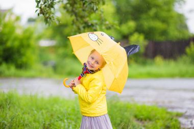 Sevimli küçük kız sarı bir şemsiye ile sarı ceketli