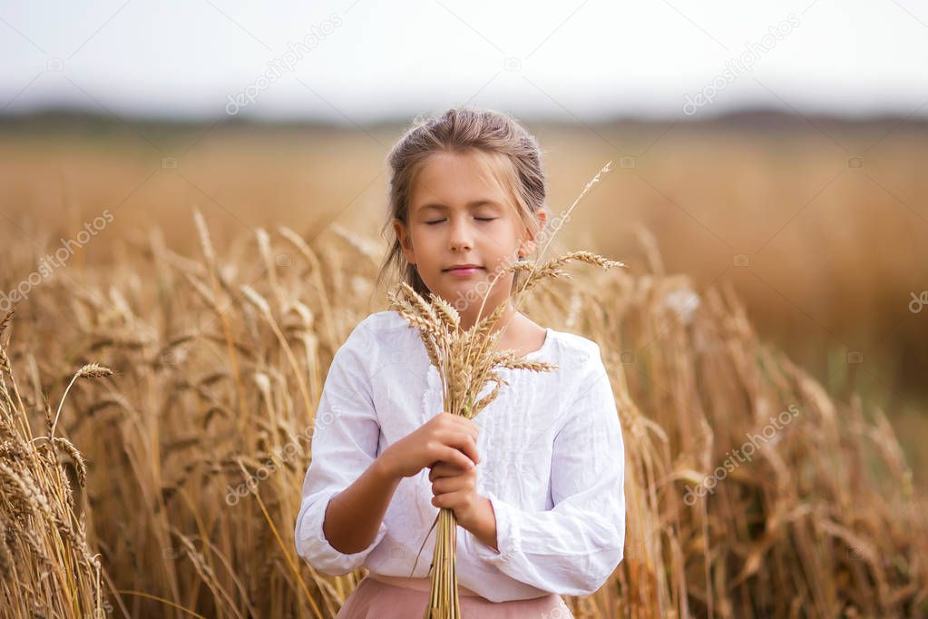 Sweet beautiful little girl in a wheaten summer field