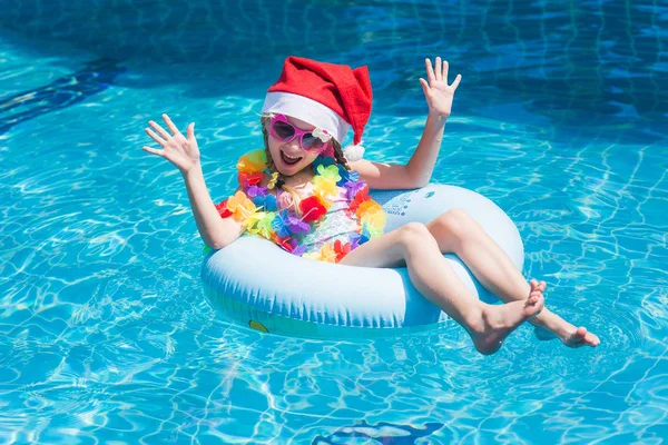 Mutlu kız Santa Claus şapka tropik tatil havuzunda bir daire içinde. Bir tatil kavramı. Yeni yıl kavramı.