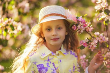Güzel, uzun saçlı bir kızın portresi. Güzel bir bahar günü çiçek açan kiraz bahçesinde eğlenen sevimli bir çocuk..
