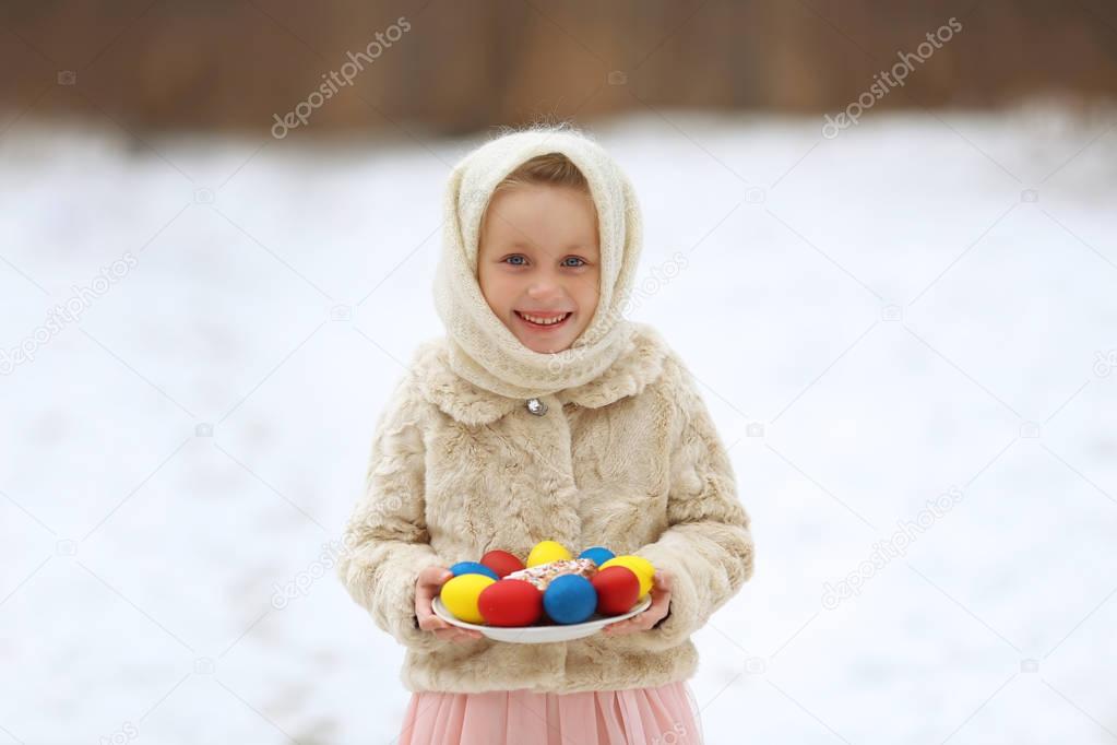 Russian girl in a national scarf with willow branches in their hands, and eggs and cake for the celebration of Easter