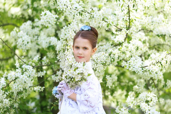 ファッショナブルな髪型とスマート ドレスでの休日の公園に咲くりんごの木の背景に甘い美しい女の子 — ストック写真