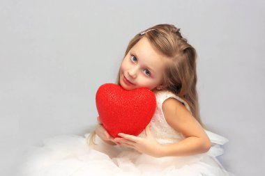 Elinde kırmızı bir kalp ile sevimli bir kız Beyaz giysili bir portresi