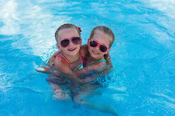 Two little funny girl in the pool on holiday