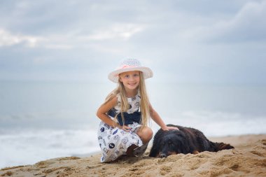 Bir köpek sahilde sarılma şapkalı şirin bir kız portresi