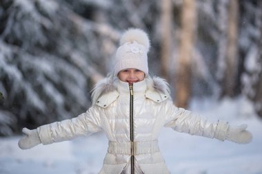 Happy girl playing snow winter day. Cold winter weather. Beautiful girl in warm coat. Winter holidays. Christmas girl in warm clothing in winter park. Fashion girl in wintertime.