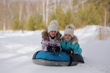 Neşeli kızlar birlikte tepeden boruya binerler. Kış tatili.